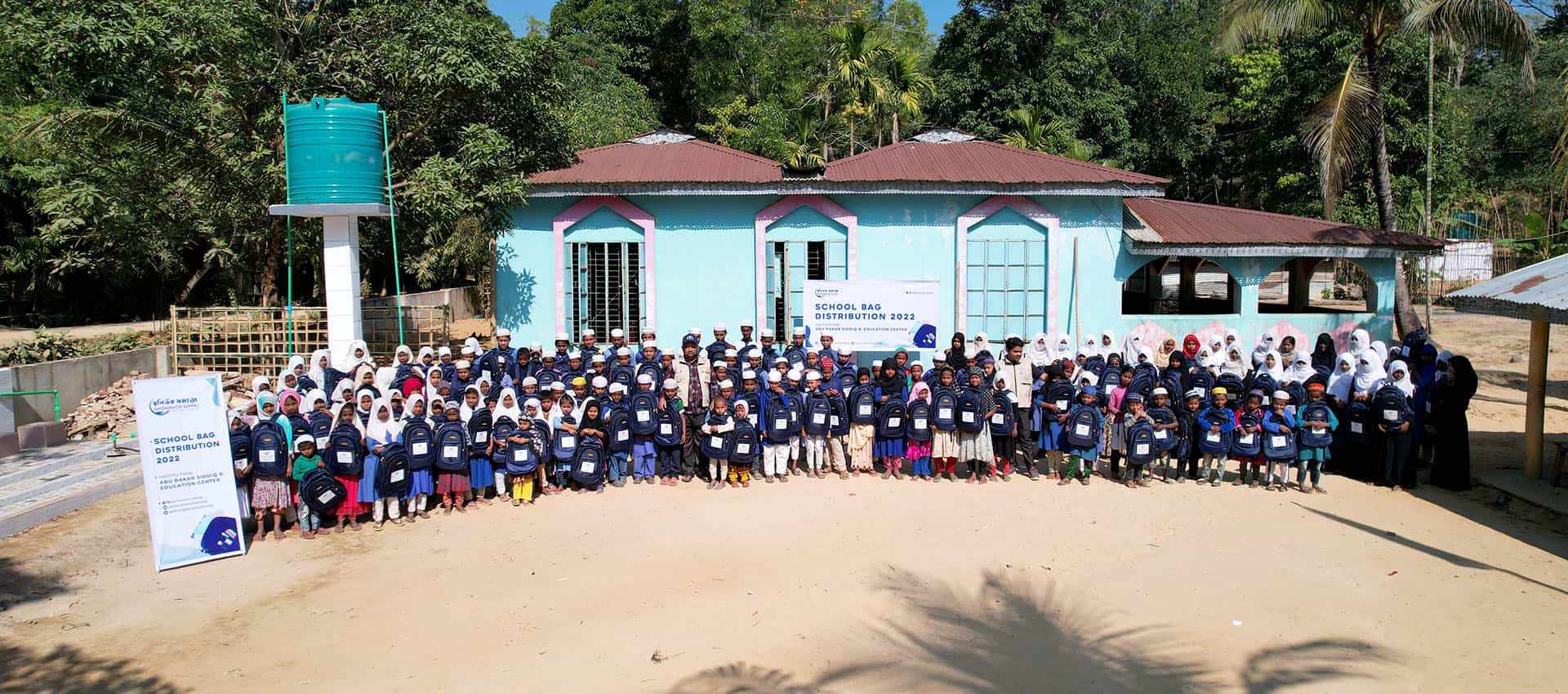 Children holding new school bags at a Shonirvor Samaj school bag distribution in 2022