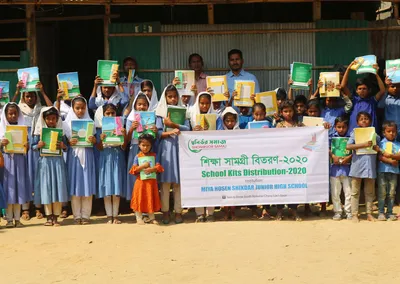 Pupils of Miya Hosen Shikdar Junior High School holding up their books at School Kits Distribution 2020