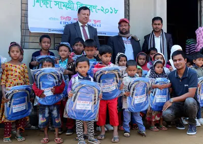 Children with new blue school bags posing with volunteers and guests