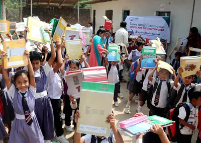 Uniformed schoolchildren cheering and holding up their new books