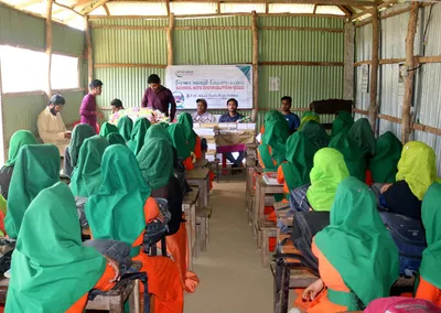 Girls in green headscarves seated in a classroom during a school kits distribution