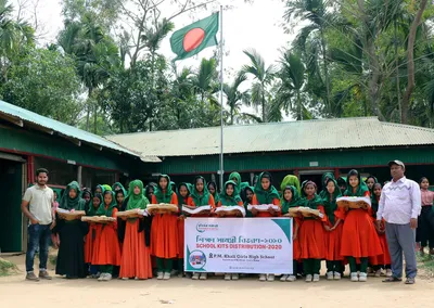 Girls in green and red school uniforms holding their kits at School Kits Distribution 2020