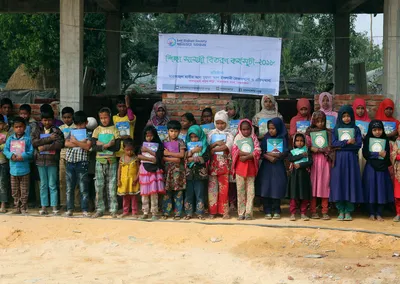 A long row of children holding new books under an education materials distribution banner