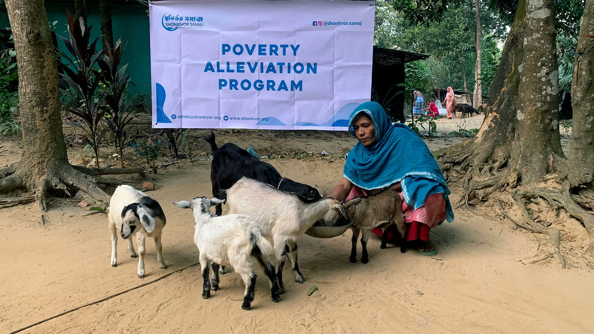 A woman feeding goats at a Poverty Alleviation Program distribution