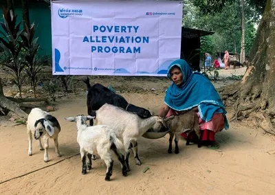 A woman feeding goats she received through the Poverty Alleviation Program