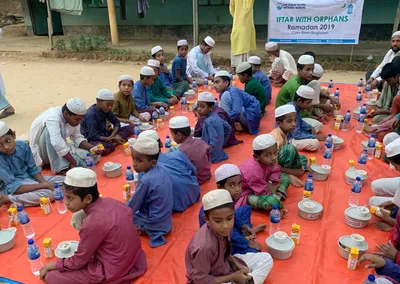 Orphan boys seated on a mat for an iftar meal