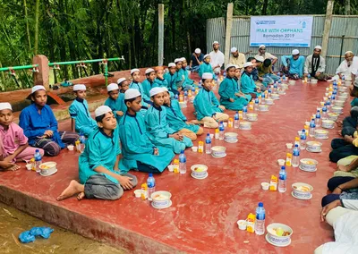 Boys seated in long rows for an Iftar with Orphans meal