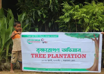 A boy beside a Tree Plantation campaign banner